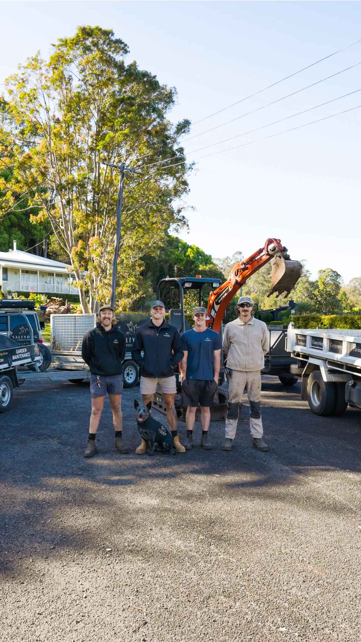 The SaltyDog crew and the kelpie in front of the digger and the trucks
