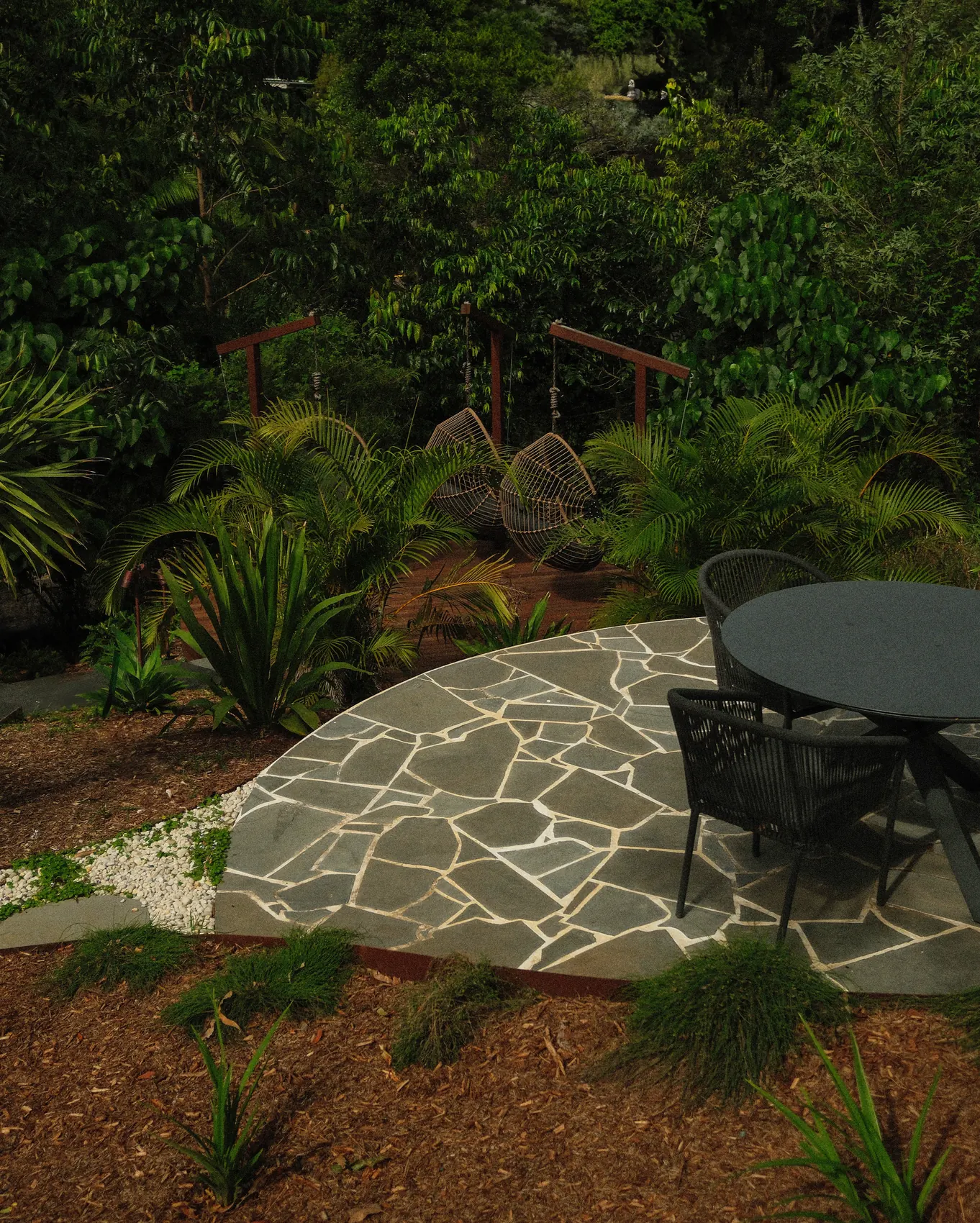 A crazy paved dining terrace kept clear under a rainforest canopy