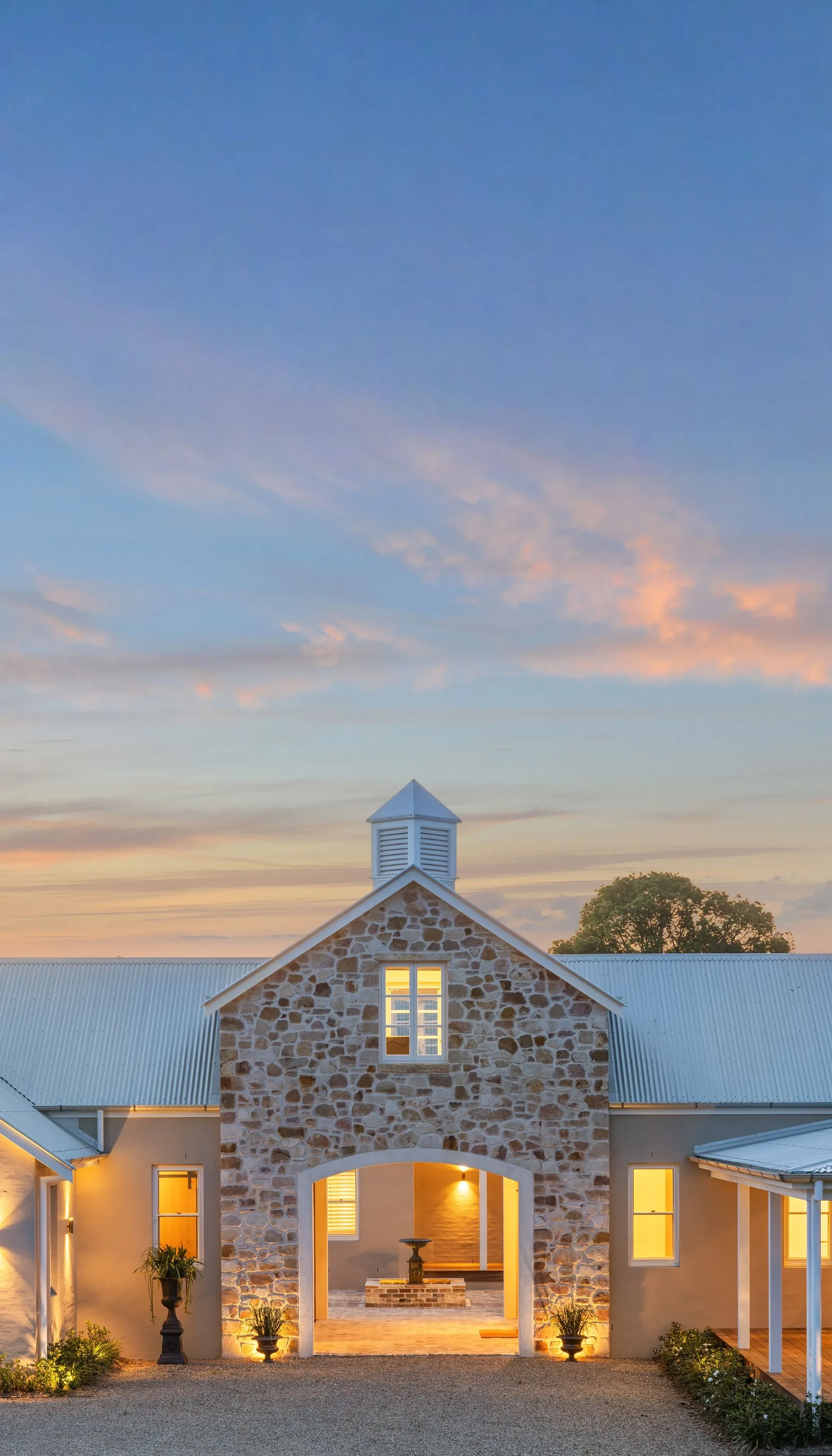 A stone barn and homestead built by SaltyDog Landscaping, lit at dusk