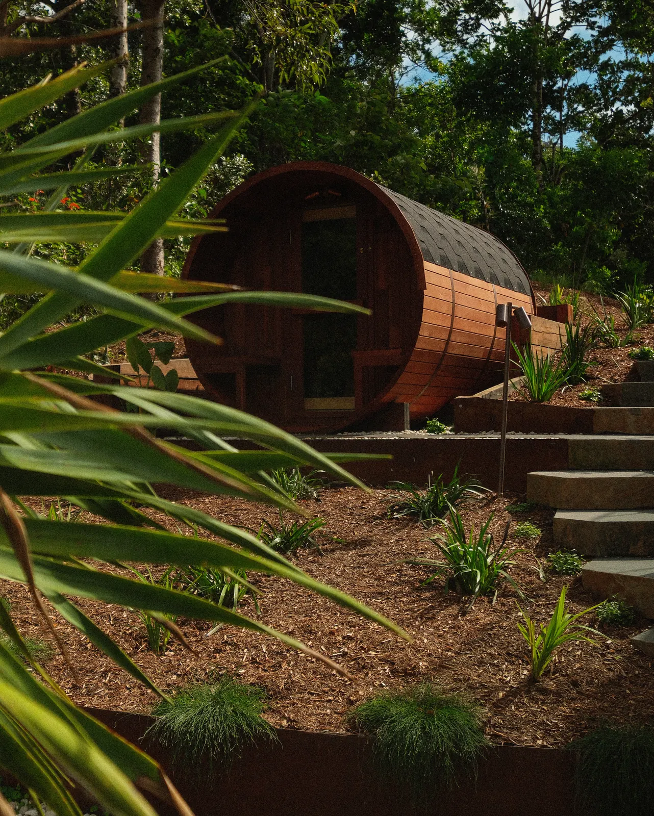 A cedar barrel sauna on a corten edged terrace, stone steps climbing past it
