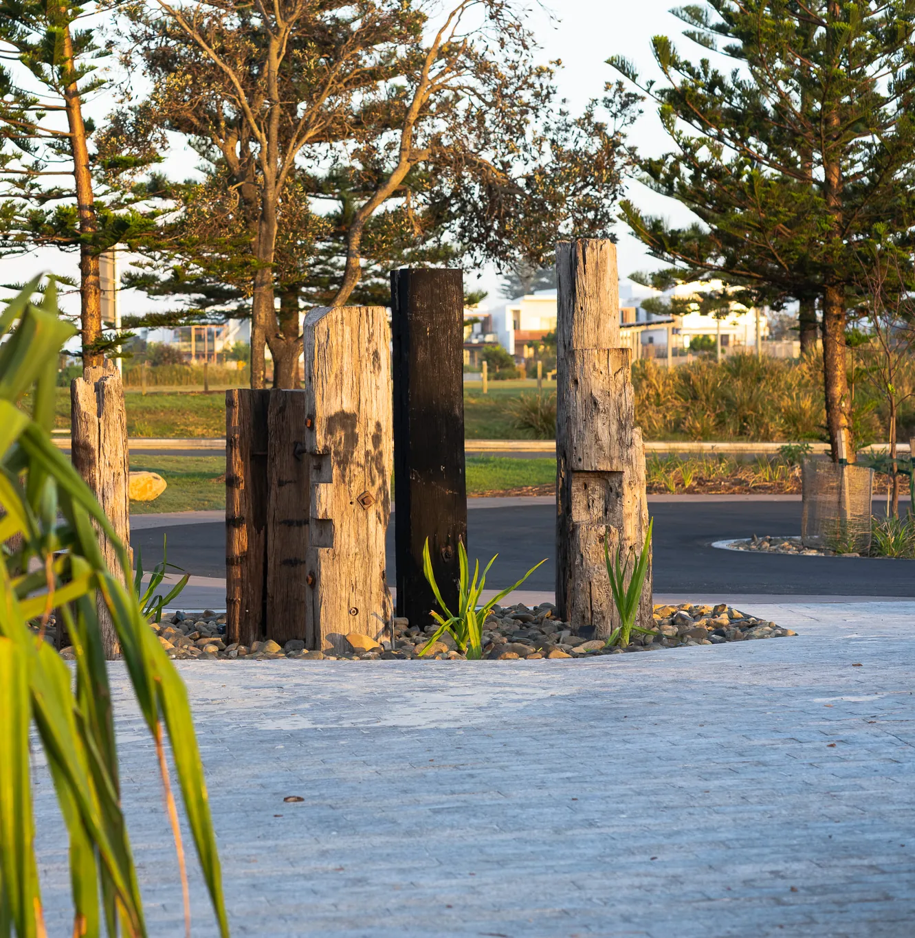 Recycled hardwood bollards standing in rock mulch beside the paving
