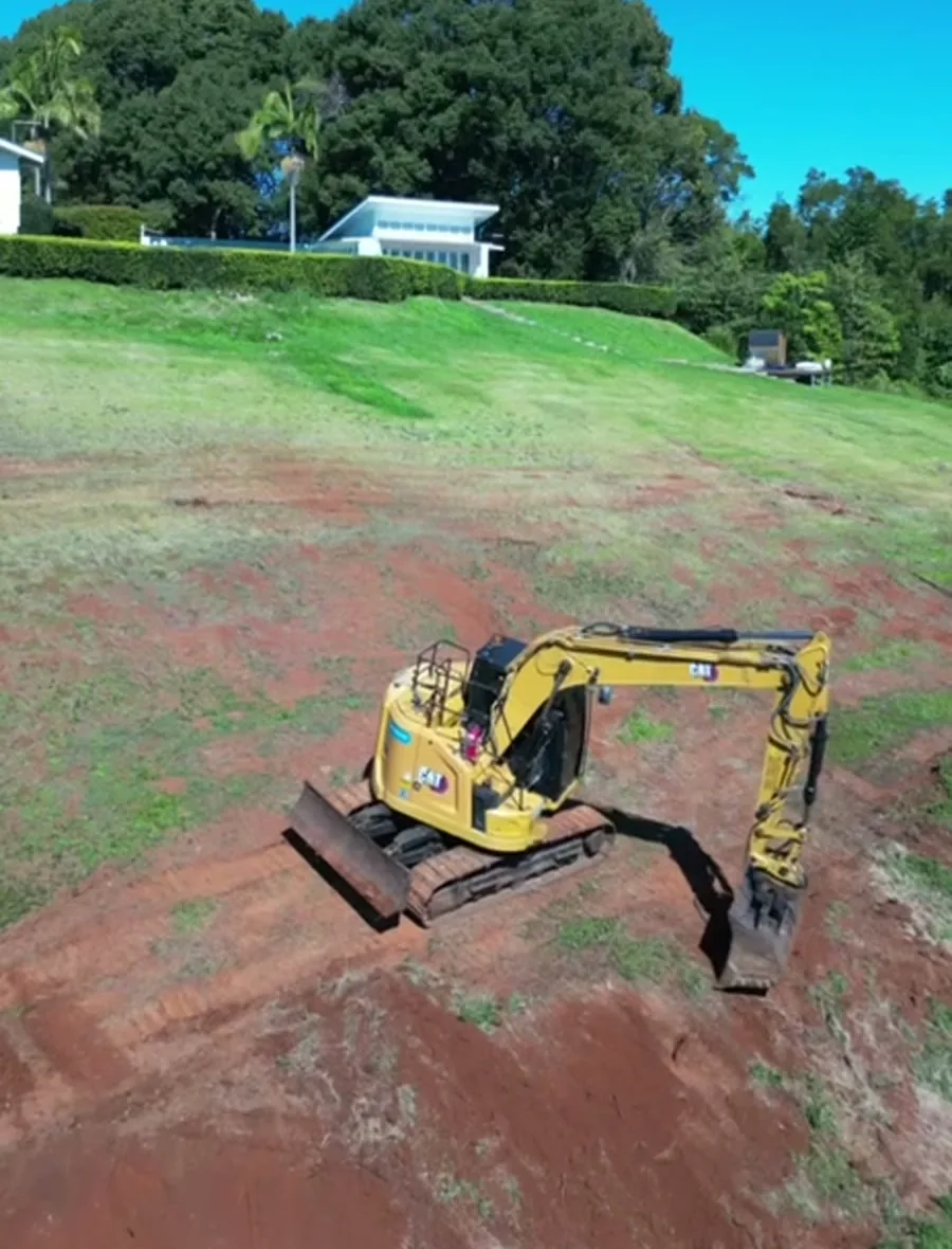 An excavator cutting a batter into a sloping site